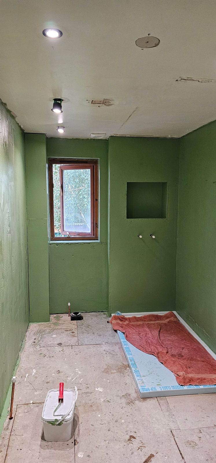 The bathroom with new green wall boards up and the floor prepared