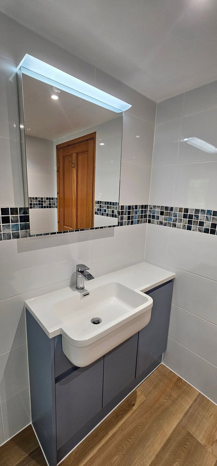 Grey vanity unit with a white basin under a mirror cabinet