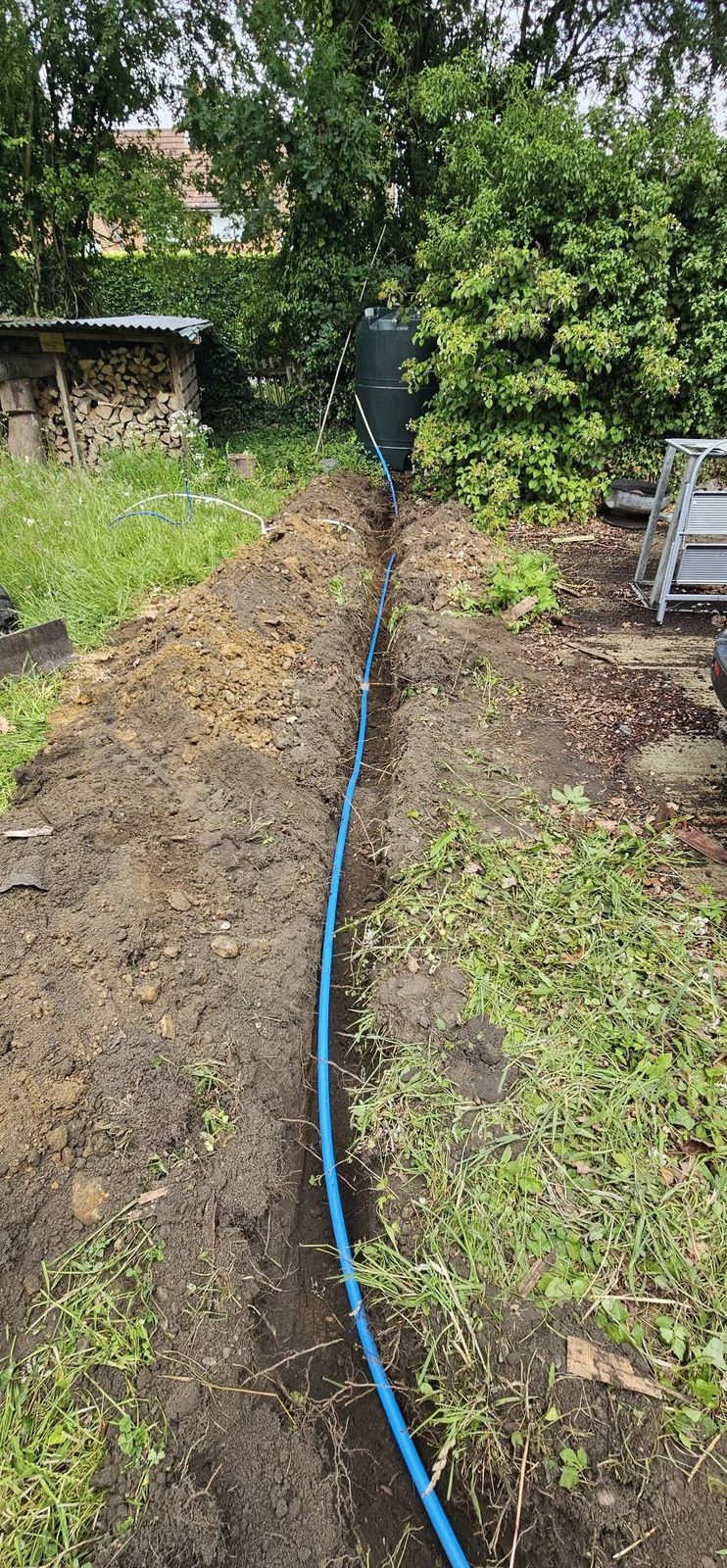 Garden trench with a new blue water pipe laid along it