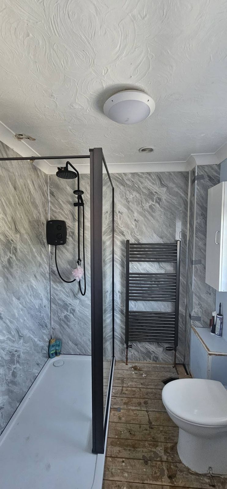 Black-framed shower enclosure with grey marble-effect wall panels