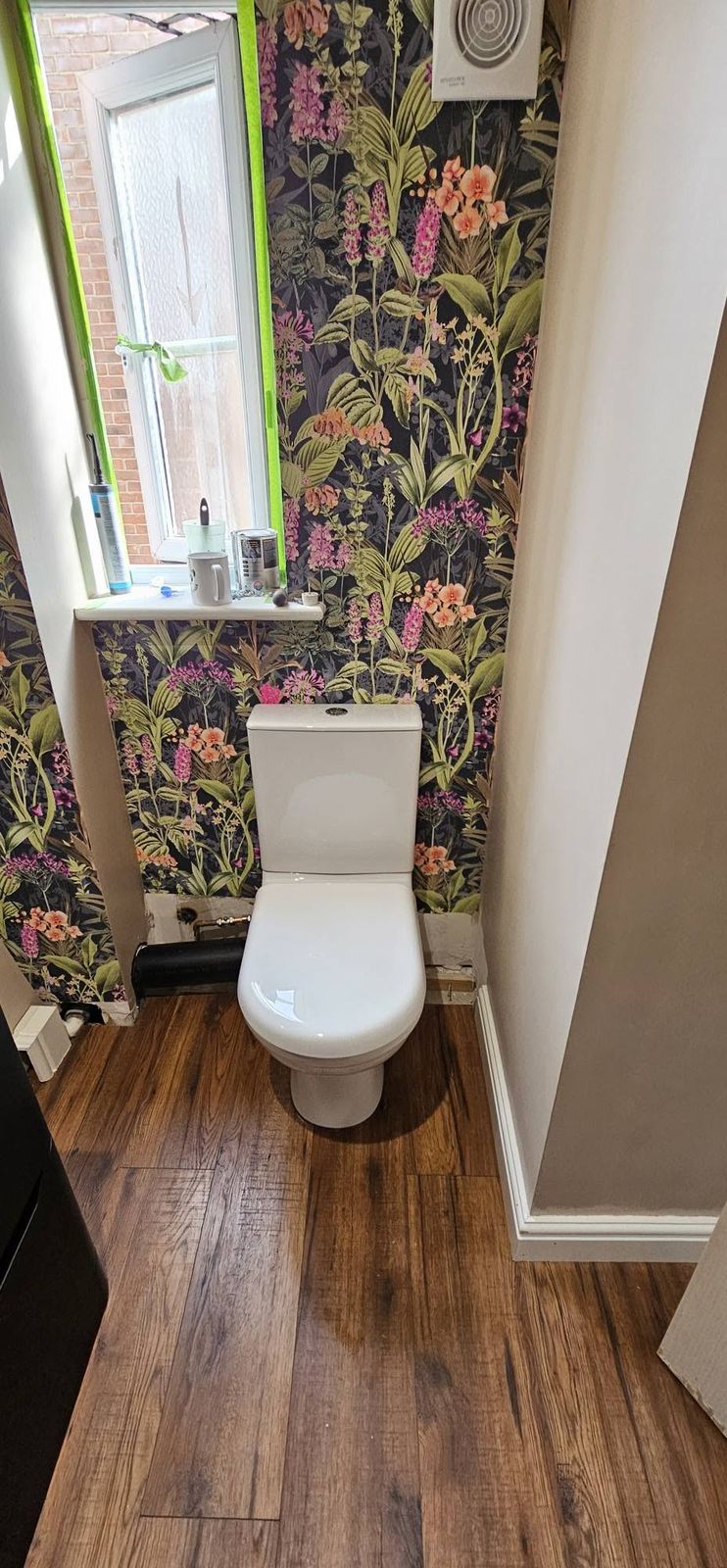 Cloakroom toilet with floral wallpaper and a wood floor