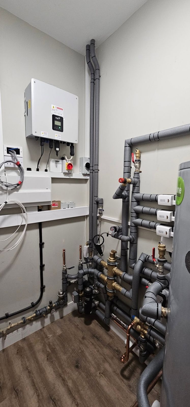 Plant room with a wall-mounted control unit and grey lagged pipework