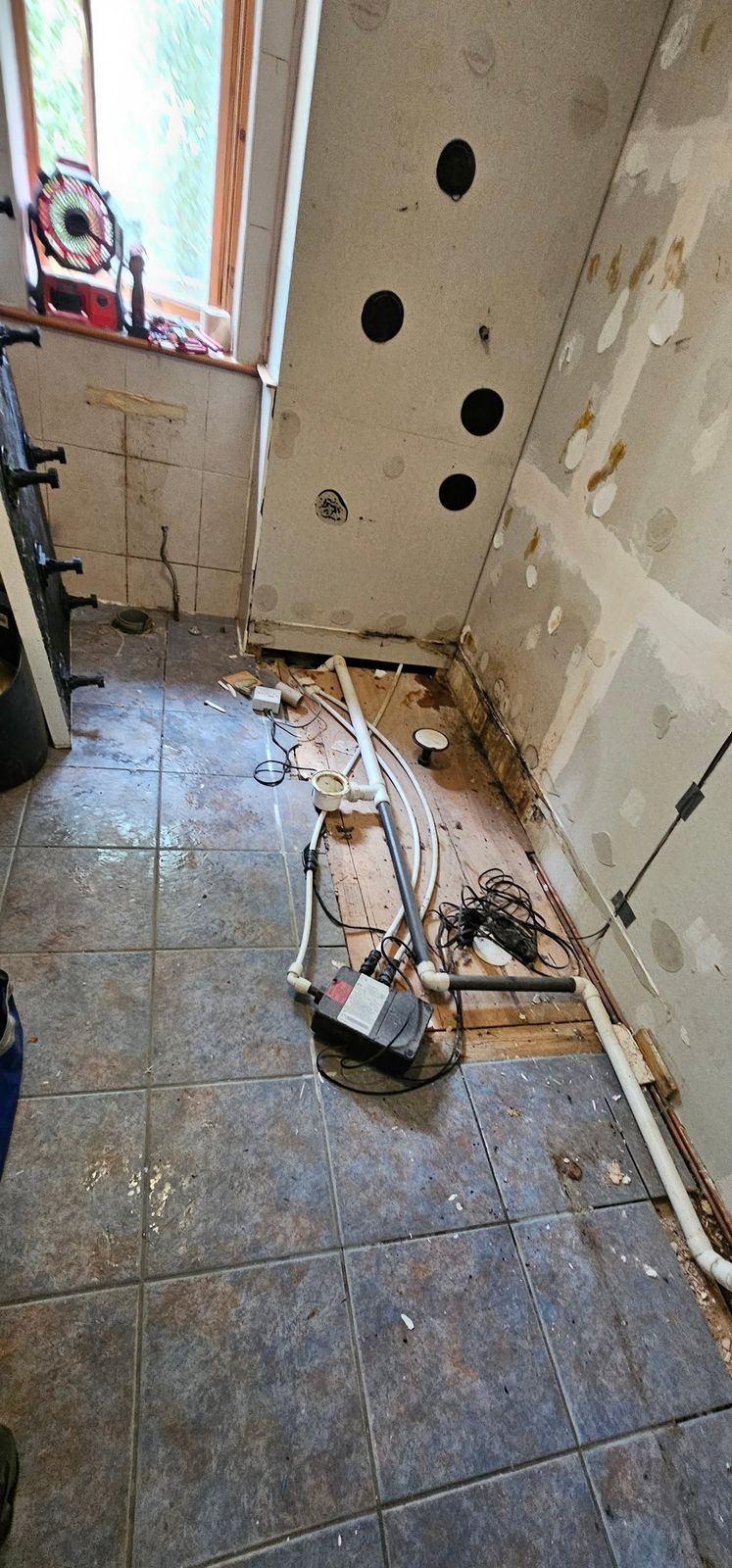 The same bathroom stripped back to the walls with the pipework exposed