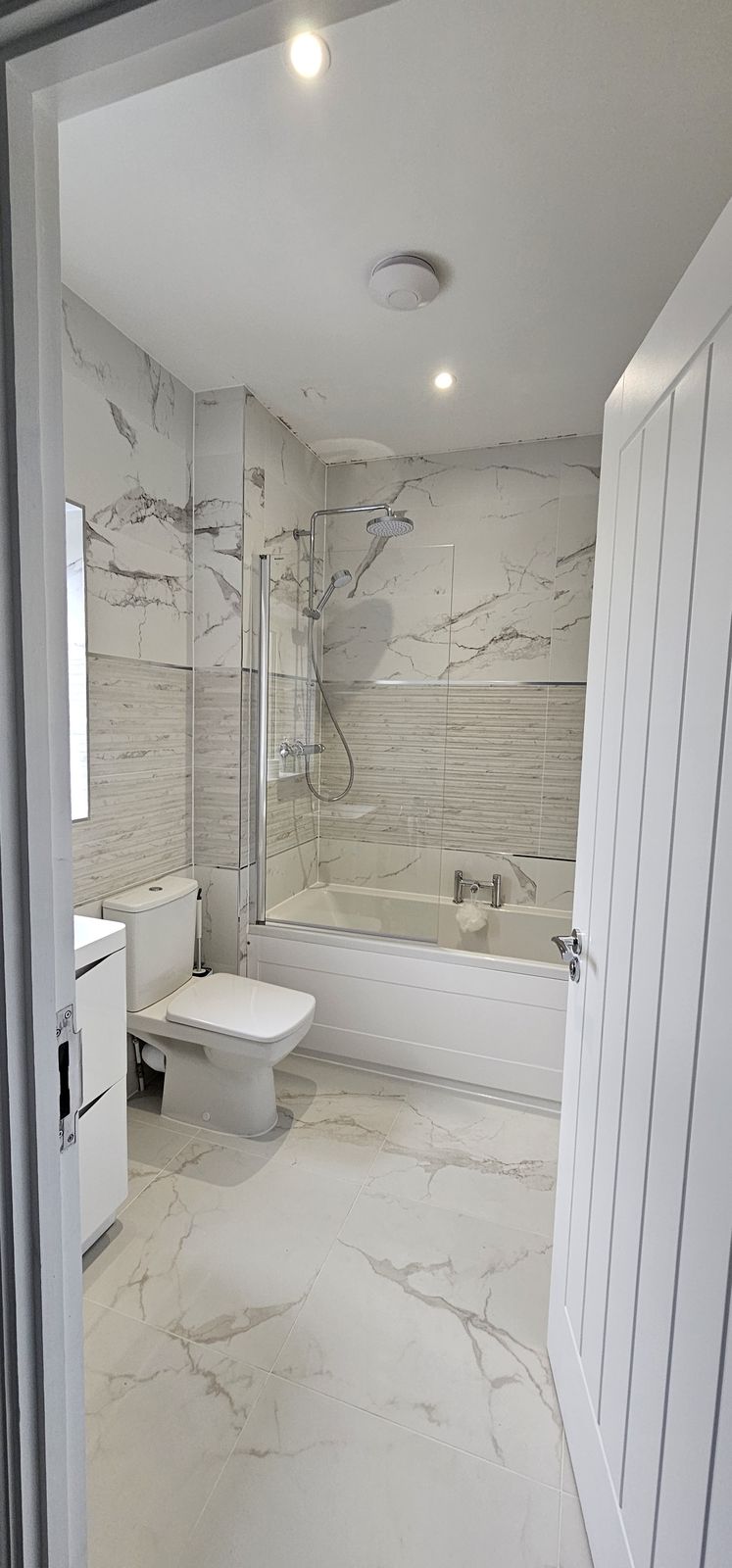 White marble-effect bathroom with a bath and shower screen