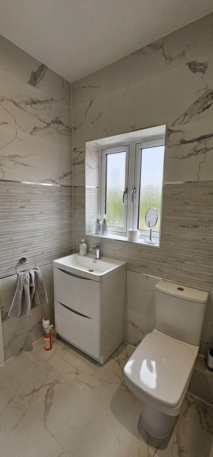 Marble-effect cloakroom with a white vanity basin and toilet